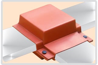 A red moulded insulating shroud closed over a four-way flat busbar joint, bolted through two flanges
