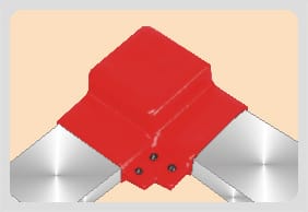 Red moulded shroud over a right-angled busbar joint, bright bar emerging from both legs and four fasteners set into the lower face.